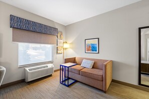 Una habitación moderna con un ventanal grande, un sofá, una mesita y un calefactor.