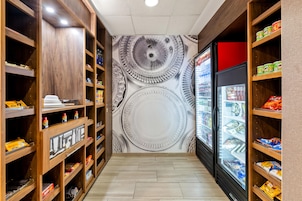 A narrow corridor with wooden shelving on both sides, stocked with various food items and beverages.