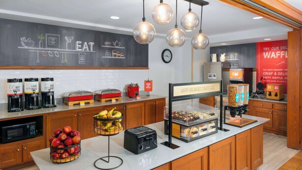 A breakfast bar with coffee machines, a toaster, and a fruit basket.