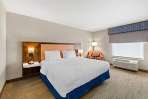 Une chambre d’hôtel équipée d’un lit, de tables de chevet, d’une lampe, d’une chaise et d’un appareil de climatisation.