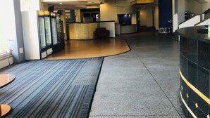 Un moderno vestíbulo de hotel con un mostrador de recepción curvo, un área de descanso y máquinas expendedoras.