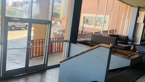 Un vestíbulo de hotel con una zona de estar, una recepción y vistas al exterior a través de amplios ventanales.