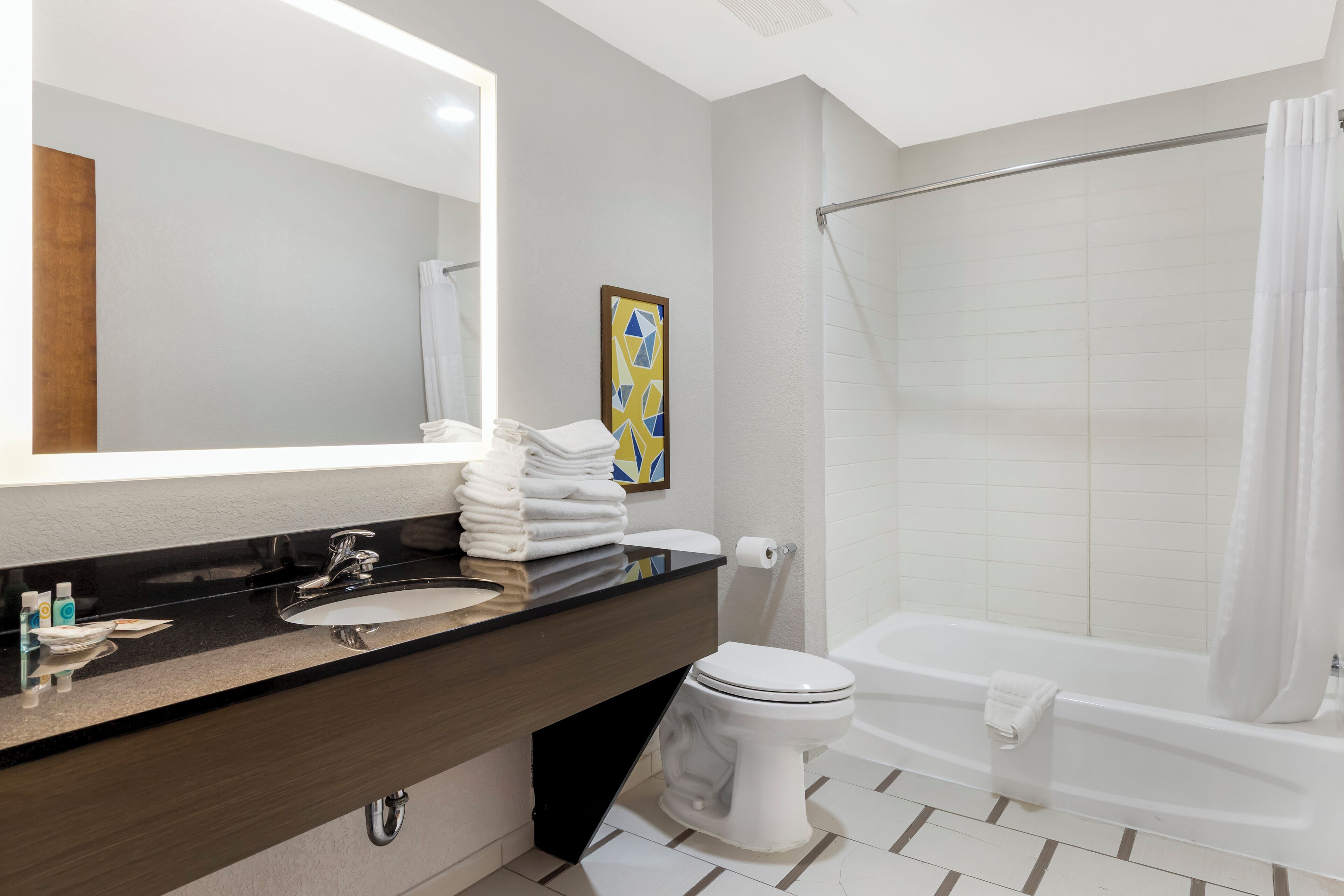 A modern bathroom with a black countertop, white sink, and a white toilet.