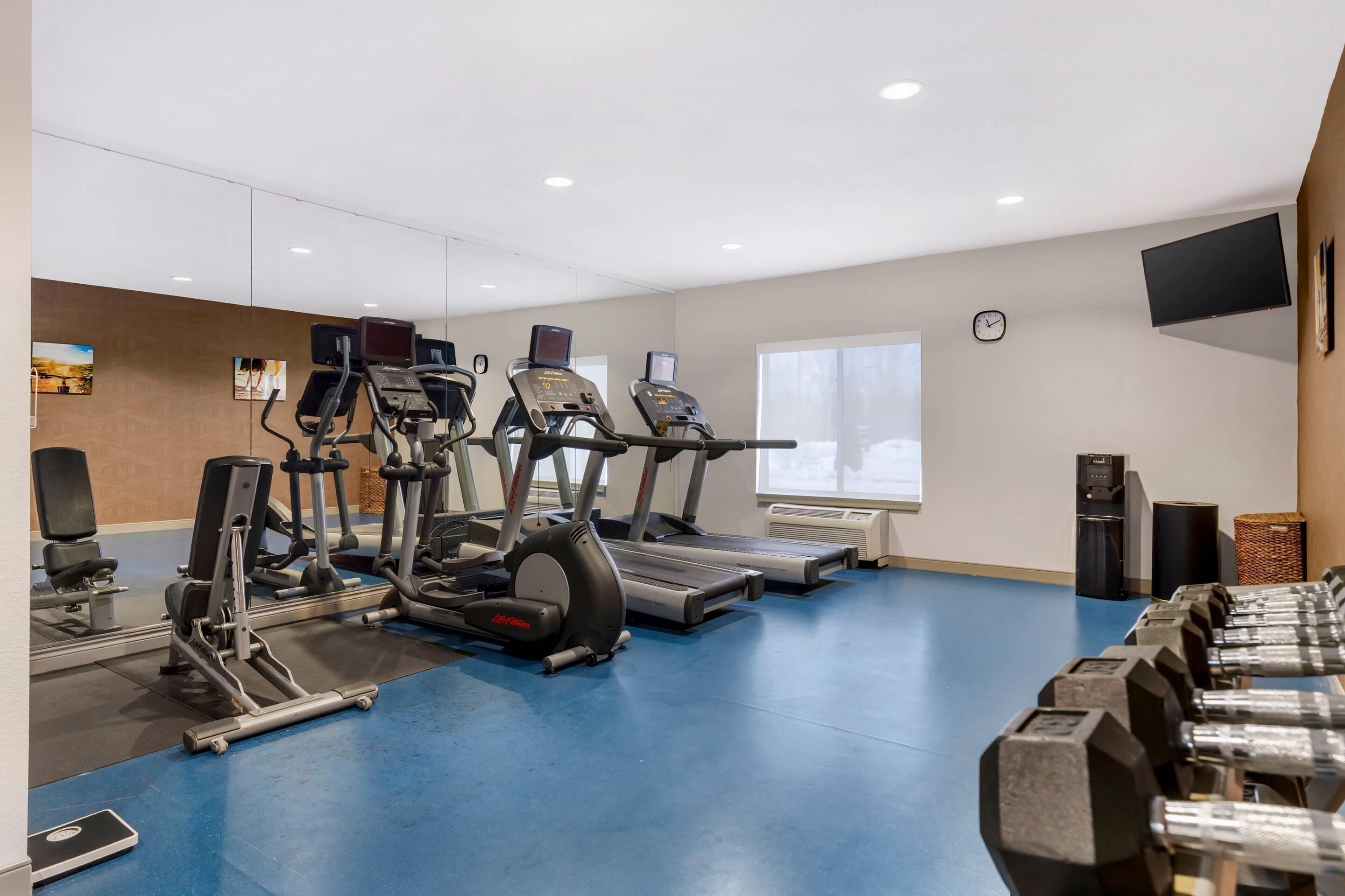 A gym with treadmills, elliptical machines, and weight benches.