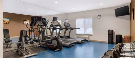 A gym with treadmills, elliptical machines, and weight benches.