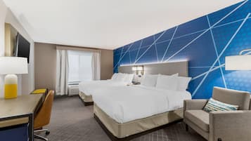Ein Hotelzimmer mit einem großen Bett, einem Schreibtisch mit Stuhl, einer Couch und einem Fernseher.
