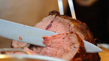 Eine Person schneidet ein gegrilltes Fleischgericht auf einem Holzschneidebrett.