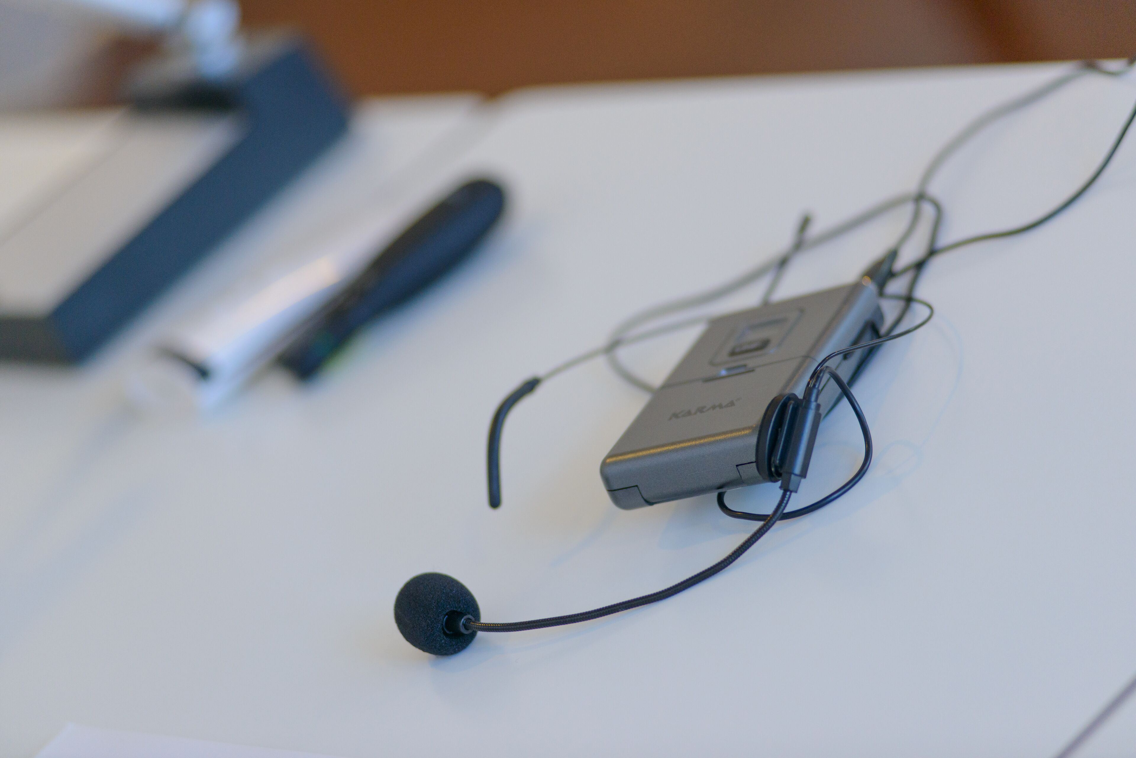 Un dispositivo con micrófono y cables sobre una superficie blanca.