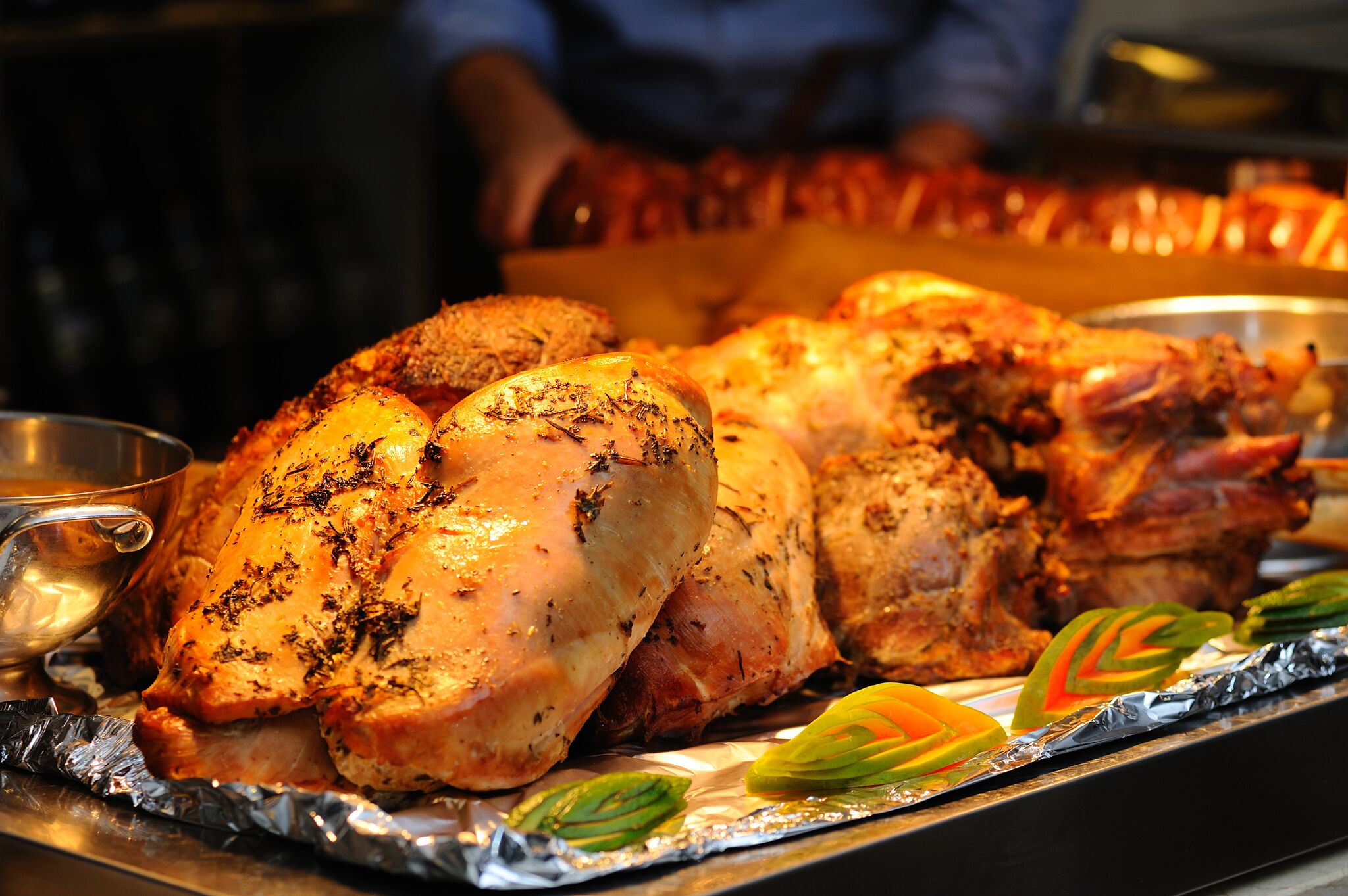 A roasted turkey on a tray with foil and garnishes.