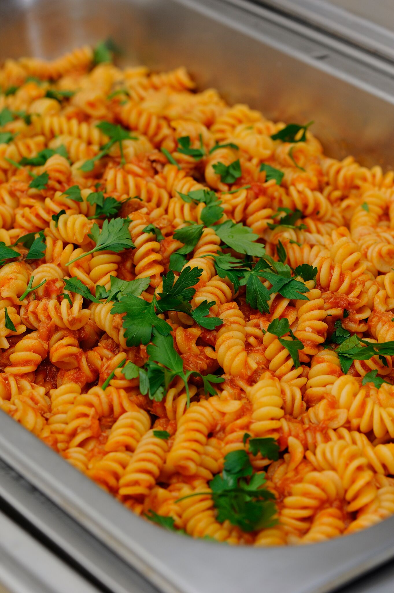 Una bandeja de pasta con salsa de tomate y adornada con perejil.