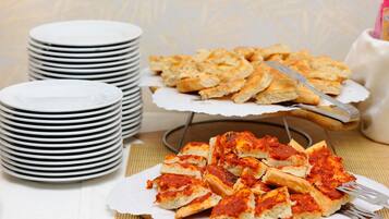 Una mesa con platos blancos apilados y una bandeja de pizza en porciones.