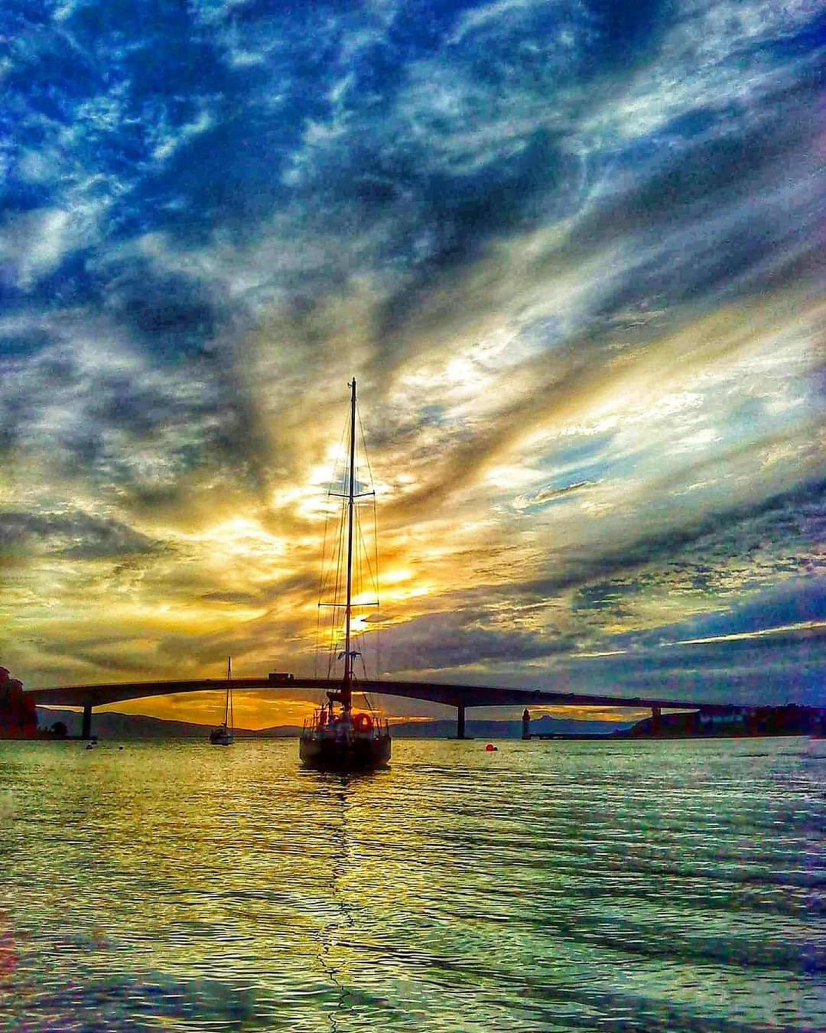 A sunset over a body of water with a bridge in the background.