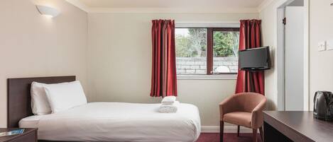A hotel room with two beds, a TV, a chair, and a desk.