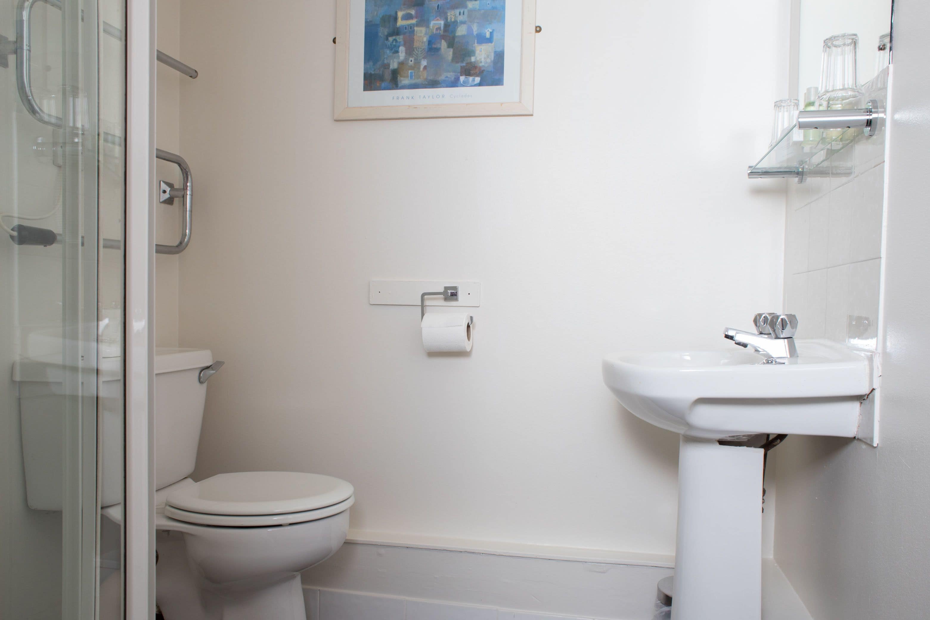 A bathroom with a toilet, a sink, and a glass shower enclosure.