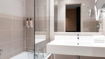 Une salle de bain moderne avec une douche à parois de verre, un lavabo blanc avec un miroir et des serviettes soigneusement pliées.