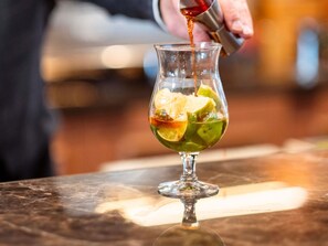 A cocktail being poured into a glass with lime slices. - Hôtel Mercure Rouen Centre Champ-de-Mars (Rouen)