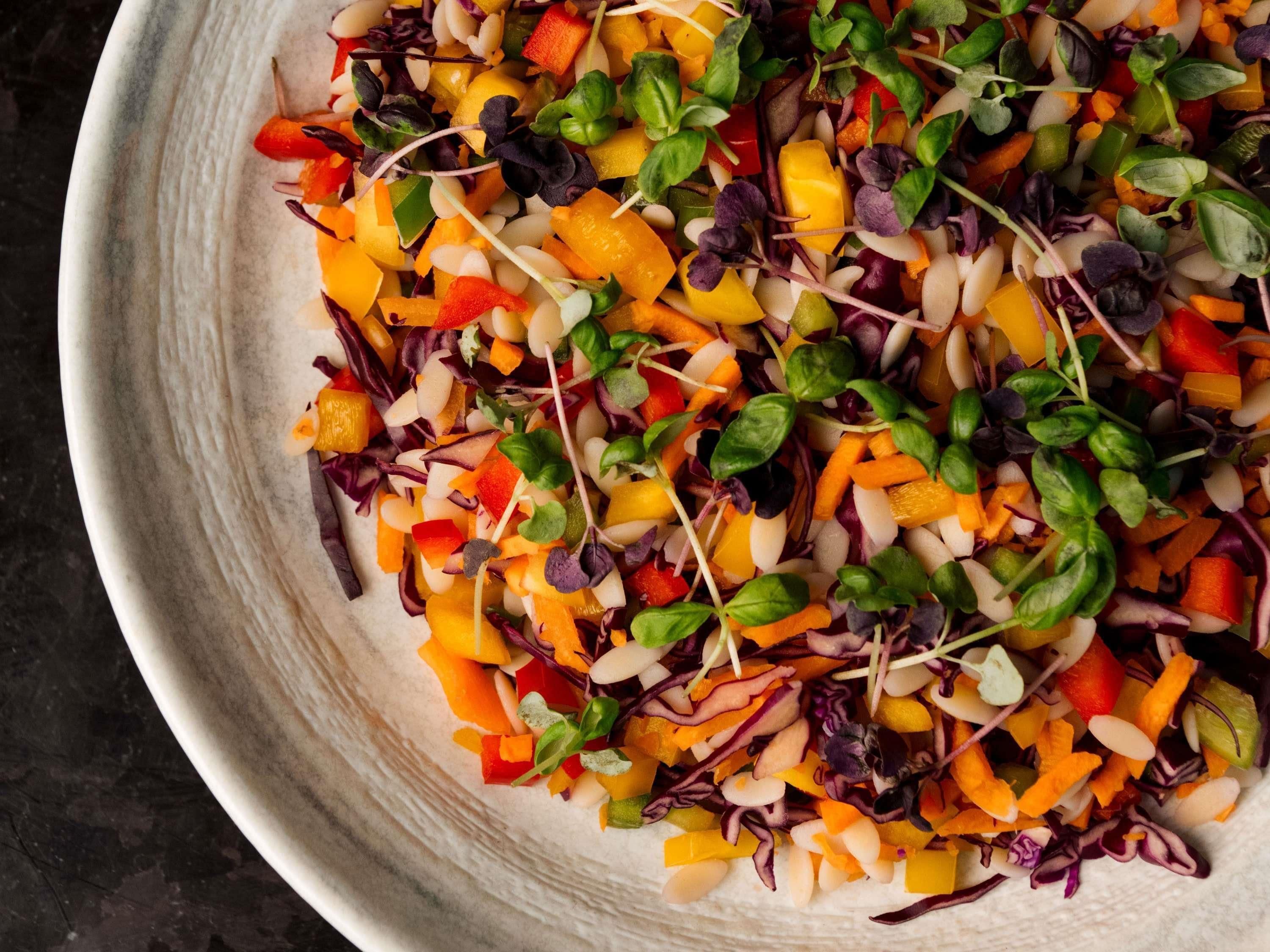 Un tazón de ensalada de verduras coloridas con diferentes tipos de hojas verdes y vegetales.