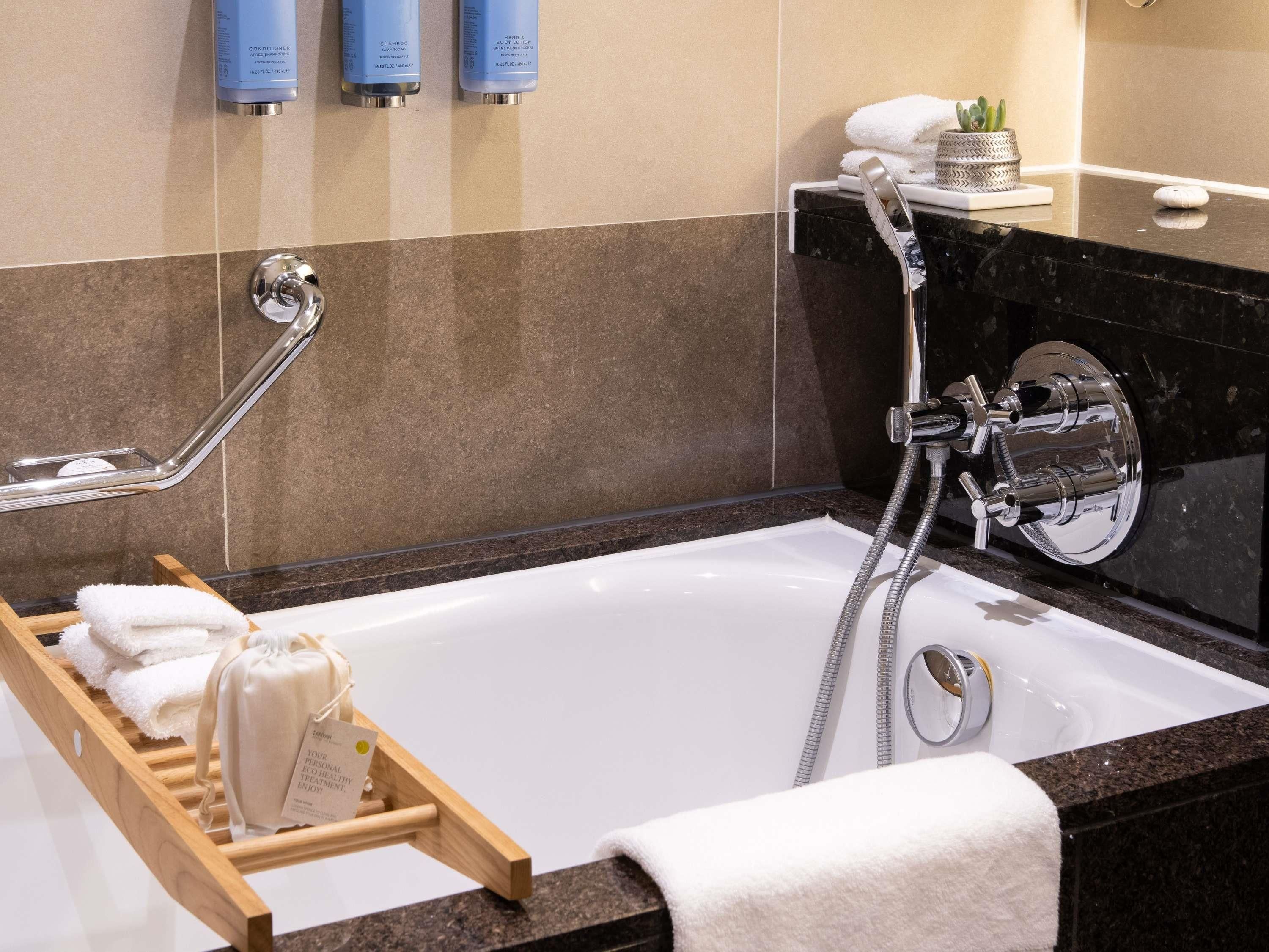 A modern bathroom with a bathtub, a shower, and a towel rack.