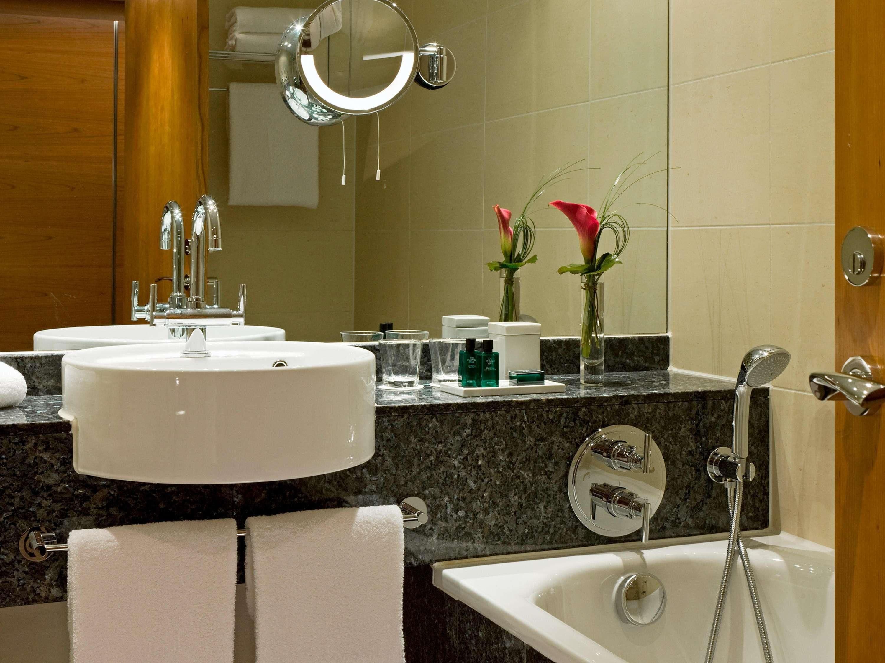 Un baño con dos lavamanos, un espejo, ducha y tocador.