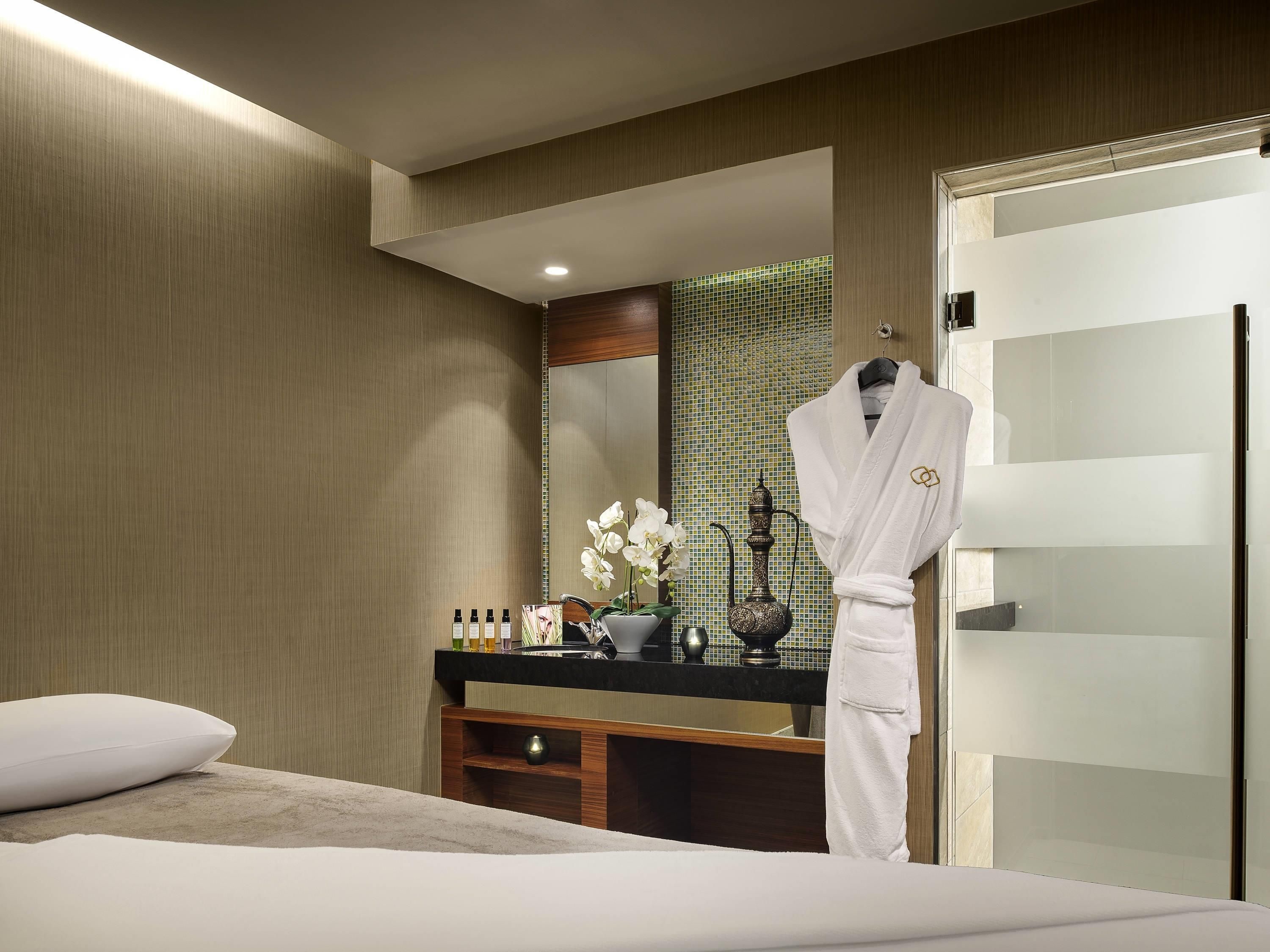 Ein Hotelzimmer mit Bett, Schminktisch mit Pflegeprodukten, Bademantel und Spiegel.