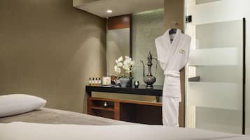 Ein Hotelzimmer mit Bett, Schminktisch mit Pflegeprodukten, Bademantel und Spiegel.