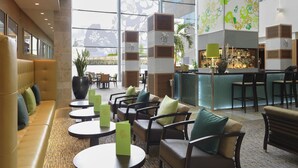 A spacious lobby with a seating area, a reception desk, and a bar. - Sofitel London Heathrow (West Drayton)
