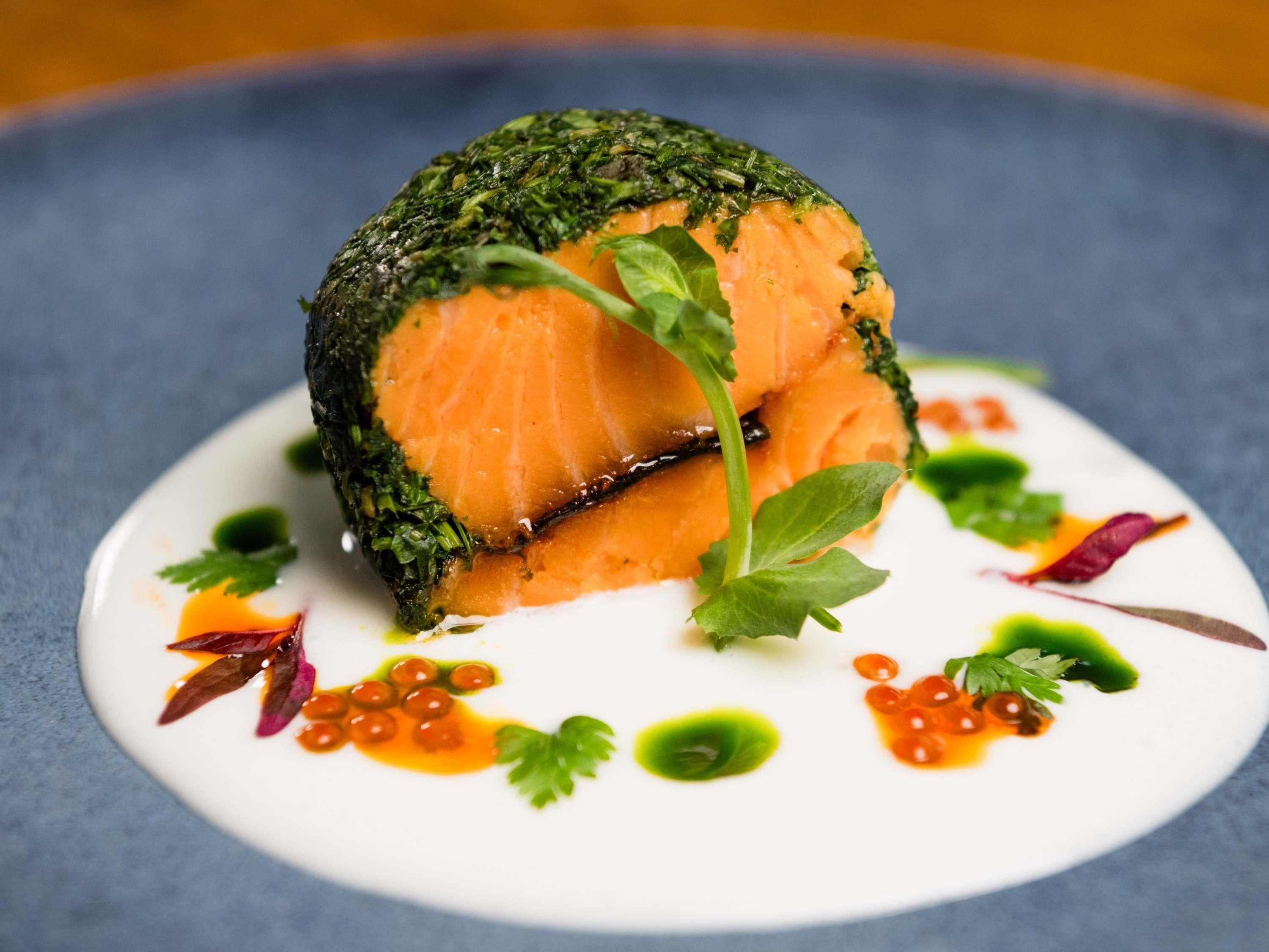 A dish with salmon and greens on a white plate.