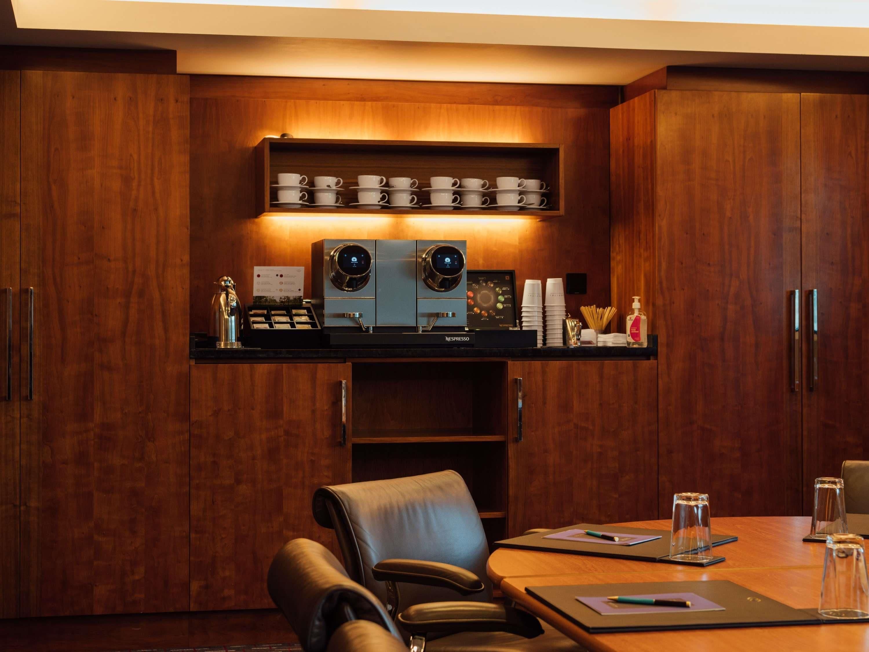 Una sala de conferencias con un armario de madera, una máquina de café y una zona de estar.