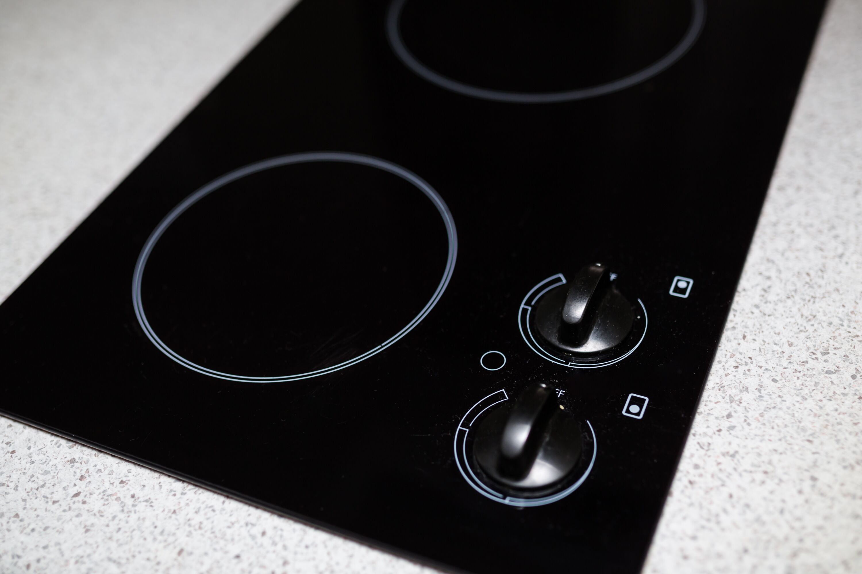 A black stovetop with three burners and two knobs.