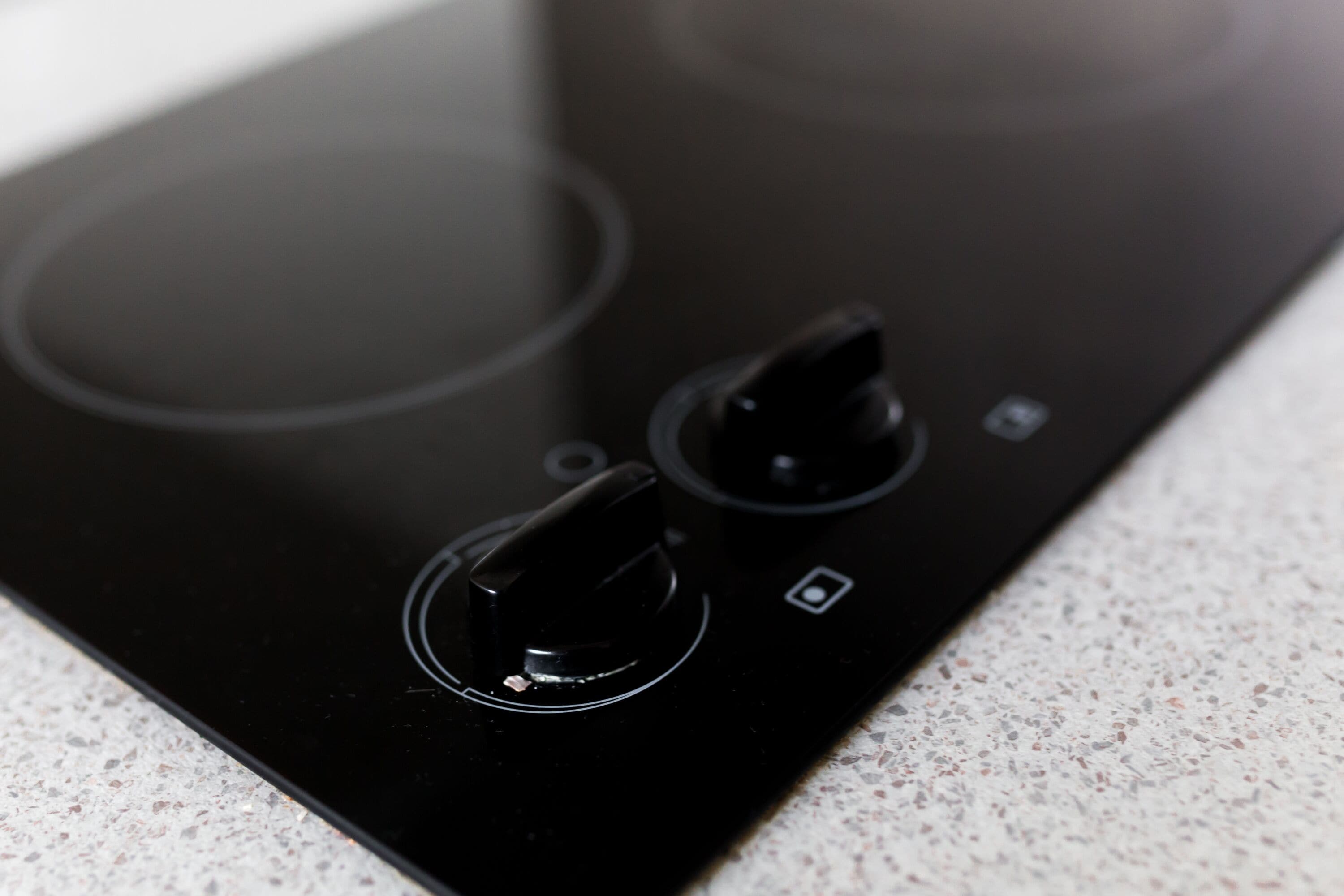 Une plaque de cuisson à induction noire, dotée de deux boutons et d’un petit panneau de commande.