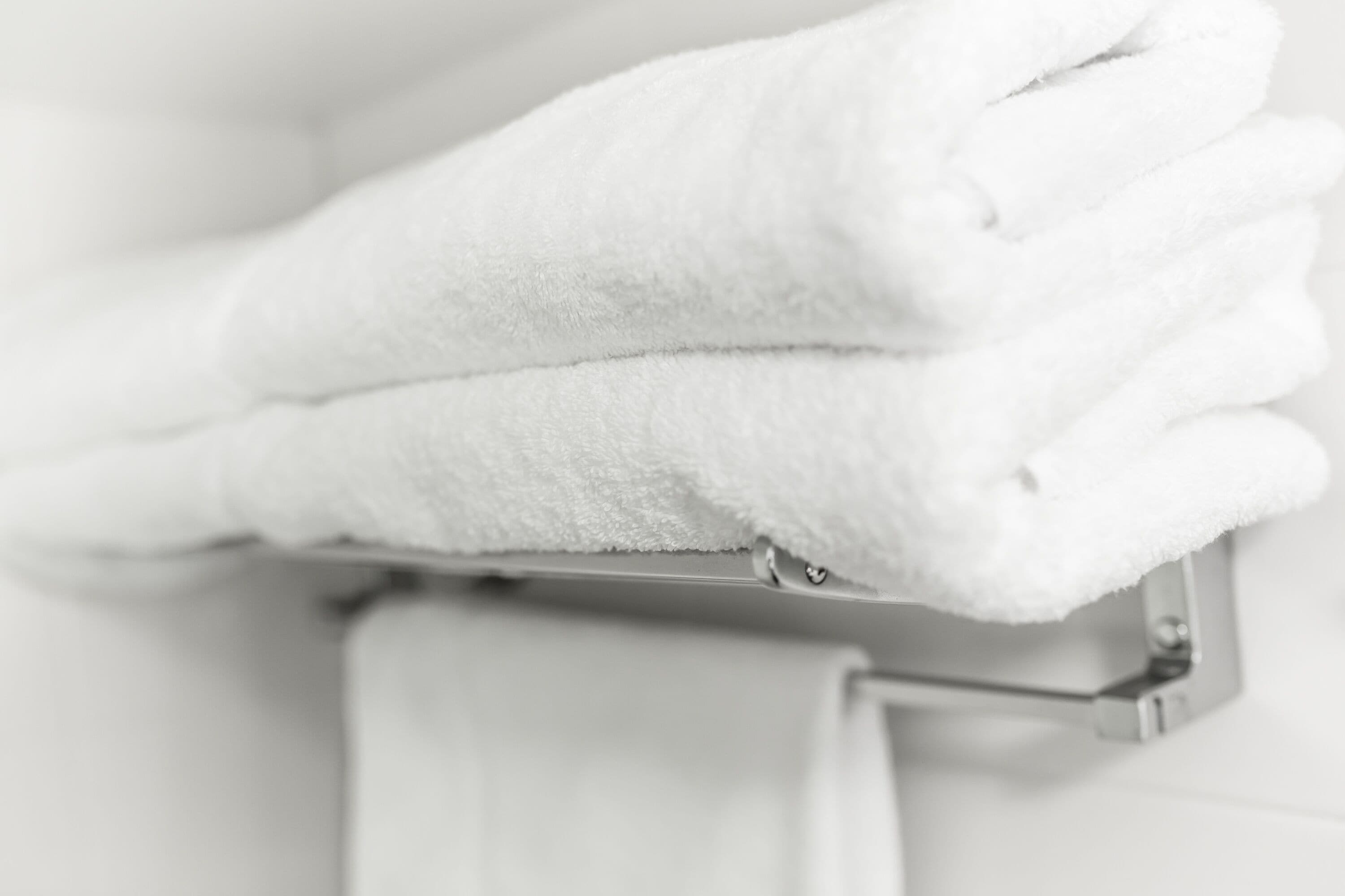A white towel folded neatly on a metal towel rack.