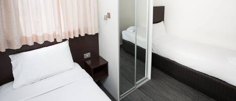 A hotel room with two beds, a nightstand, a mirror, and a door leading to a bathroom.