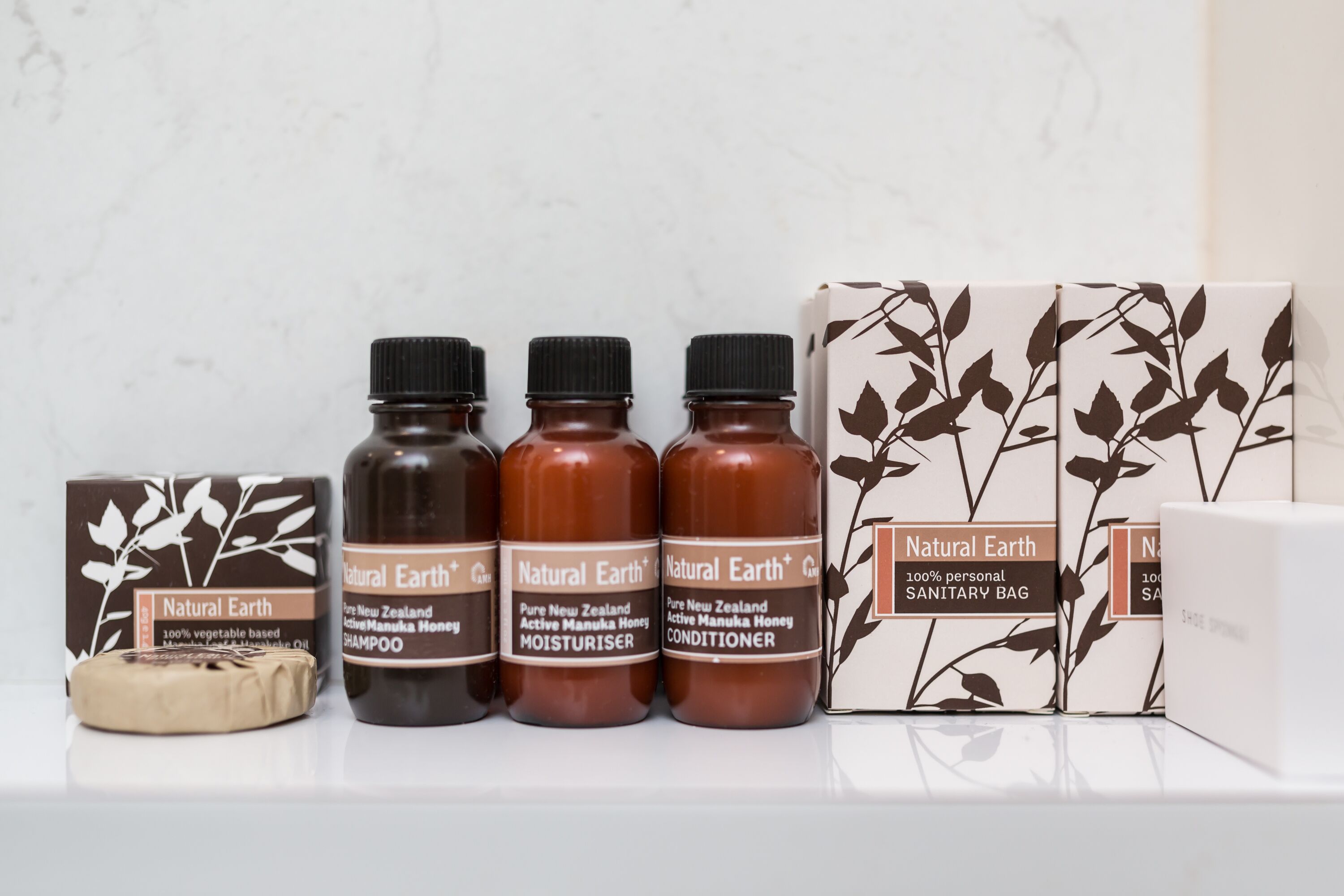 A shelf with Natural Earth products including shampoo, conditioner, and a personal sanitary bag.