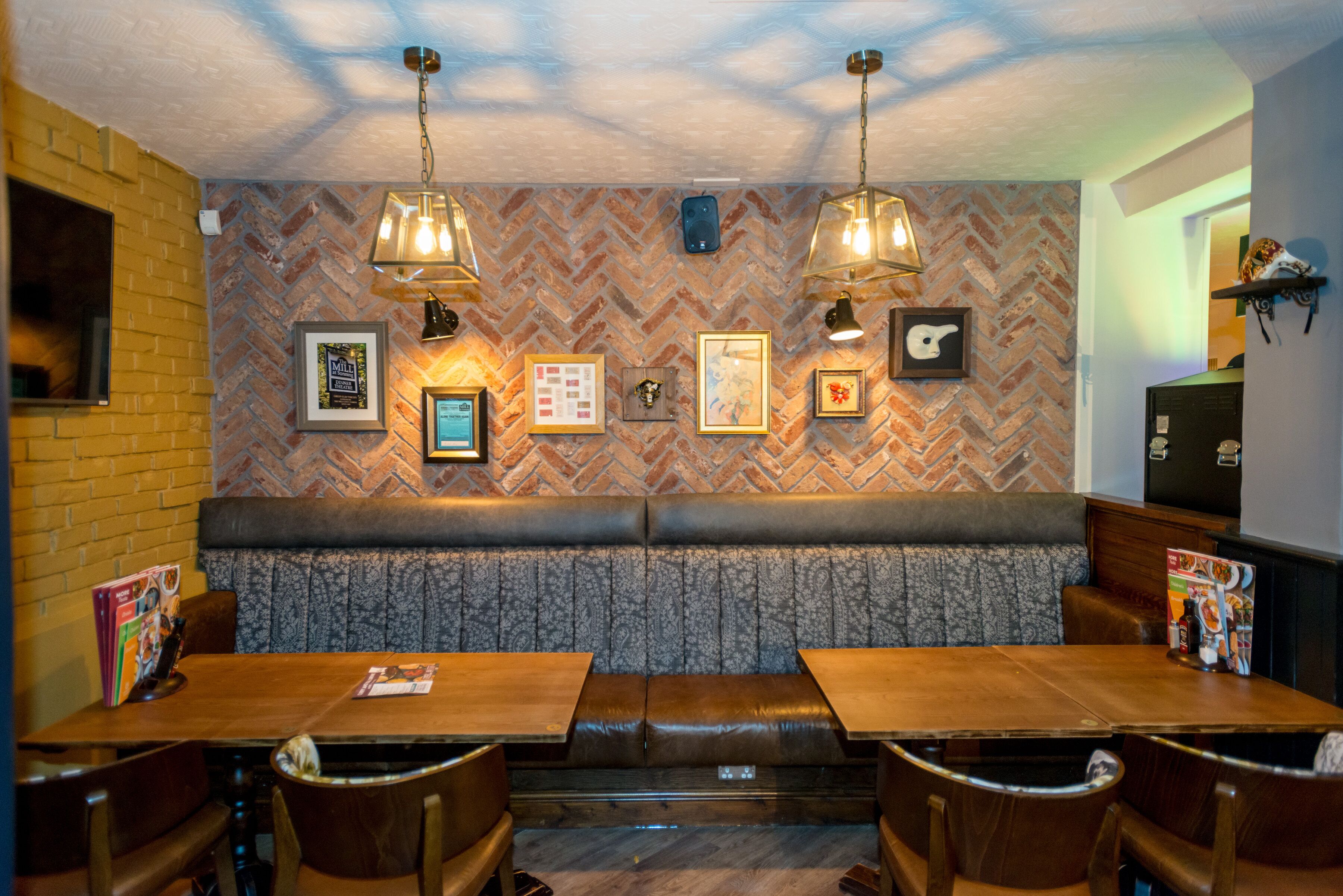 Un restaurante con pared de ladrillo, patrón de espiga y una zona de estar con bancos de madera.