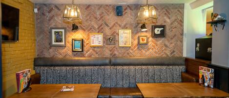 Un restaurante con pared de ladrillo, patrón de espiga y una zona de estar con bancos de madera.