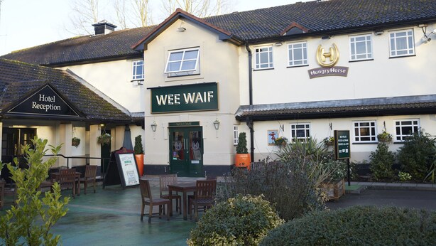 Un edificio con un letrero que dice "WEE WAIF" y otro letrero que indica "Recepción del Hotel".