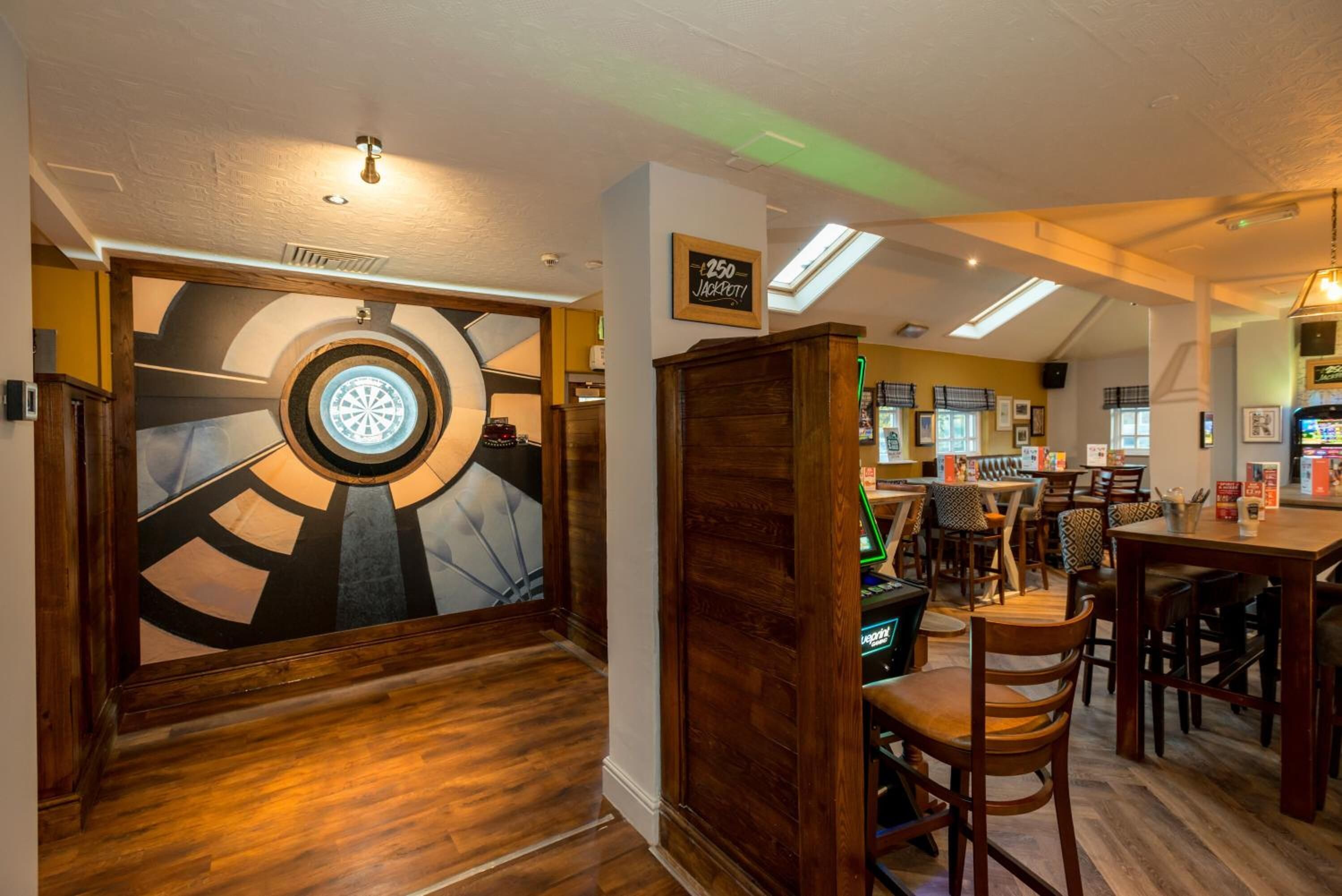 A restaurant interior with a dartboard, wooden furniture, and a sign indicating a 250-jacket price.
