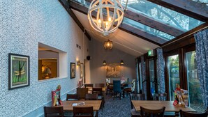 Un restaurante con techo alto, paredes con diseños y una mezcla de sillas de madera y tapizadas.