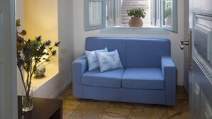 Un pasillo con un sofá azul, una planta en maceta y vistas de una escalera.