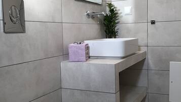 A modern bathroom with a toilet, a sink, and a mirror.