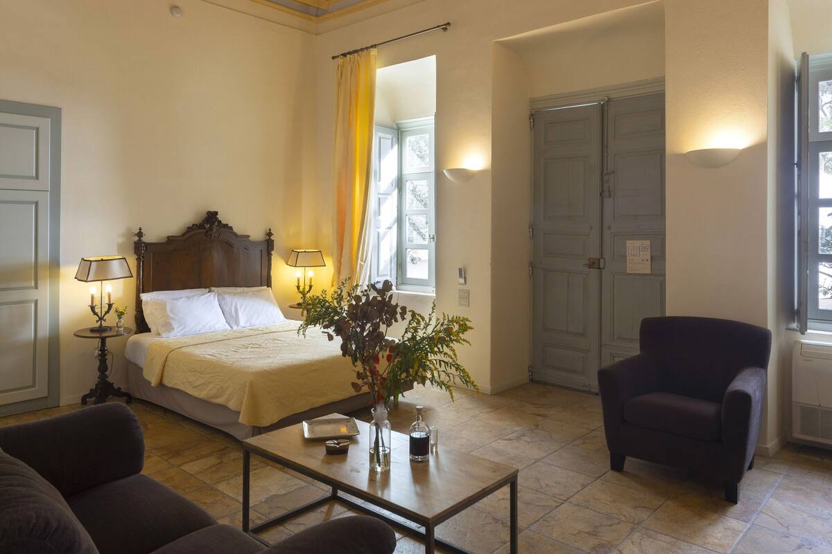 Quarto com cama, mesa de centro, cadeira e decoração no teto.