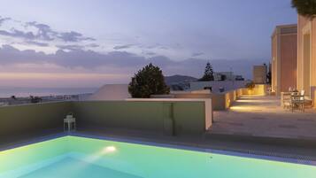A rooftop swimming pool with a view of the sea and mountains.