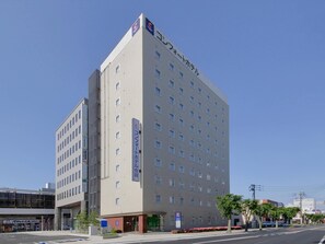 A multi-story hotel with a modern facade, featuring a prominent sign on the side and a clear sky in the background. - Comfort Hotel Saga (Saga)