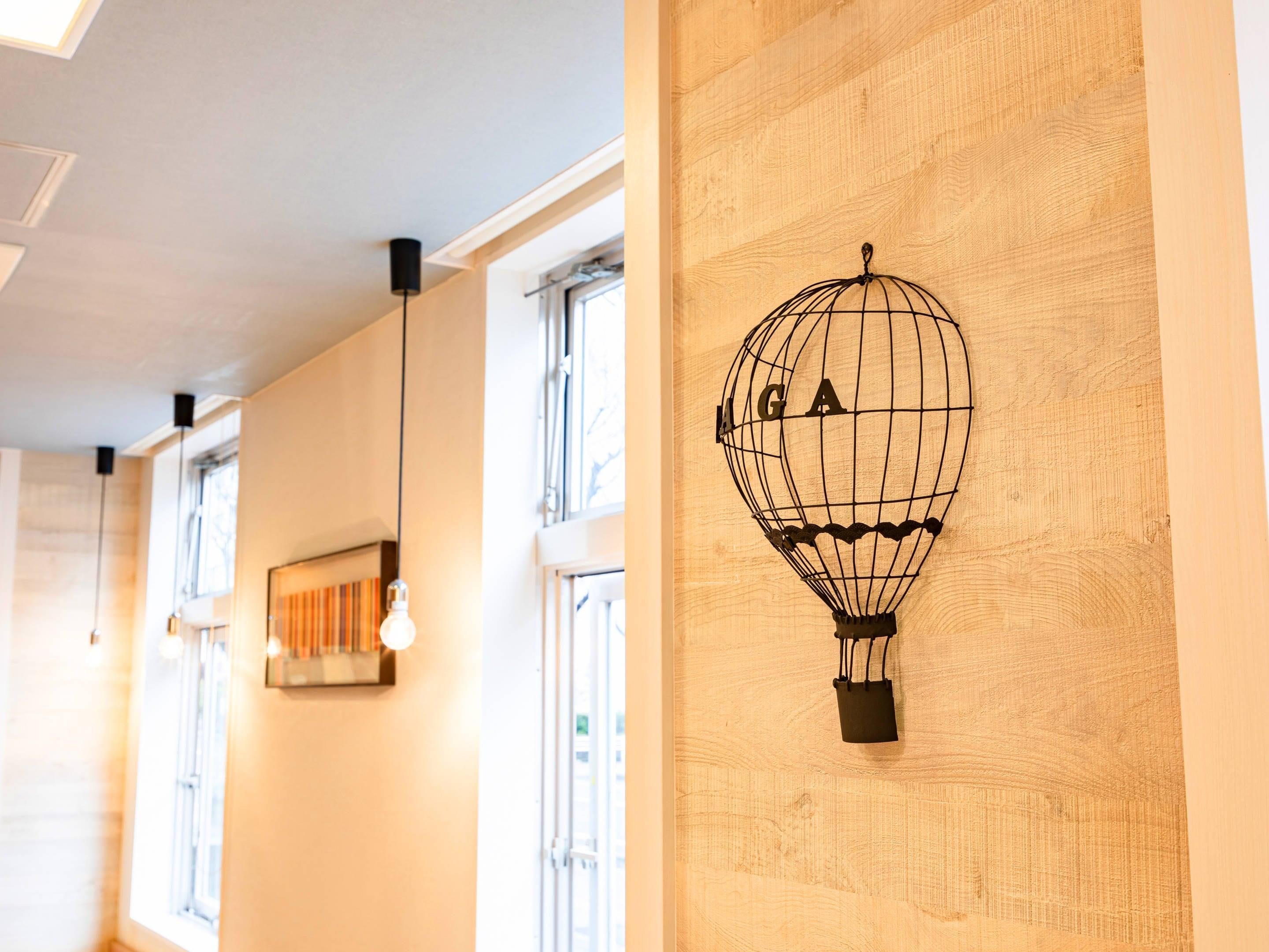 Un pasillo con paredes de madera, un candelabro colgante y un adorno de globo aerostático en la pared.