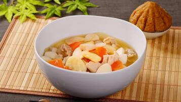Un bol de soupe contenant des légumes et de la viande, posé sur un tapis en bambou.
