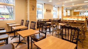A restaurant with wooden tables and chairs, large windows, and a counter area. - Comfort Hotel Saga (Saga)