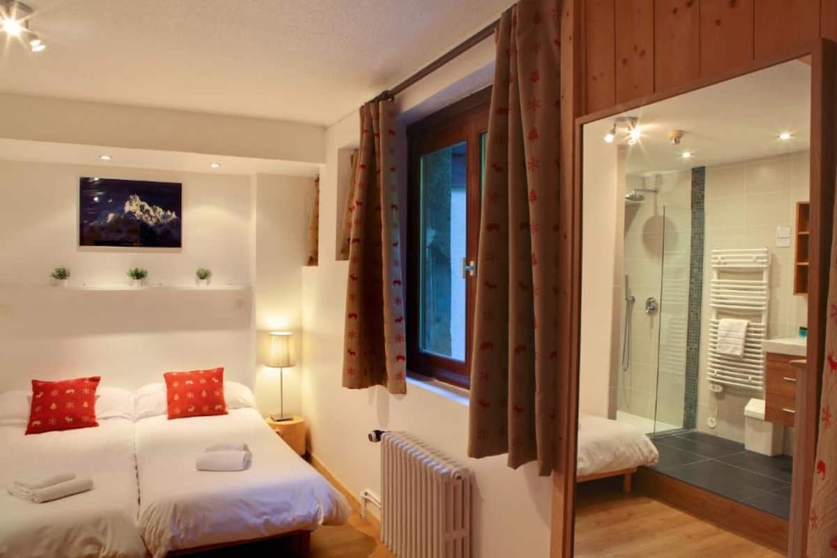 A hotel room with a bed, a nightstand, a radiator, and a shower area.