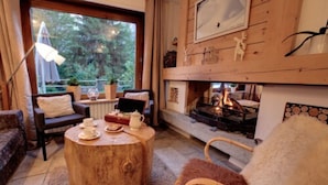 Una sala de estar acogedora con una mesa de centro de madera, asientos cómodos, una chimenea y vistas al exterior.