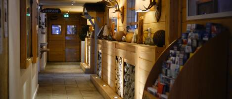 A wooden hallway with a fireplace, antlers, and a sign reading "ASCENSEUR".