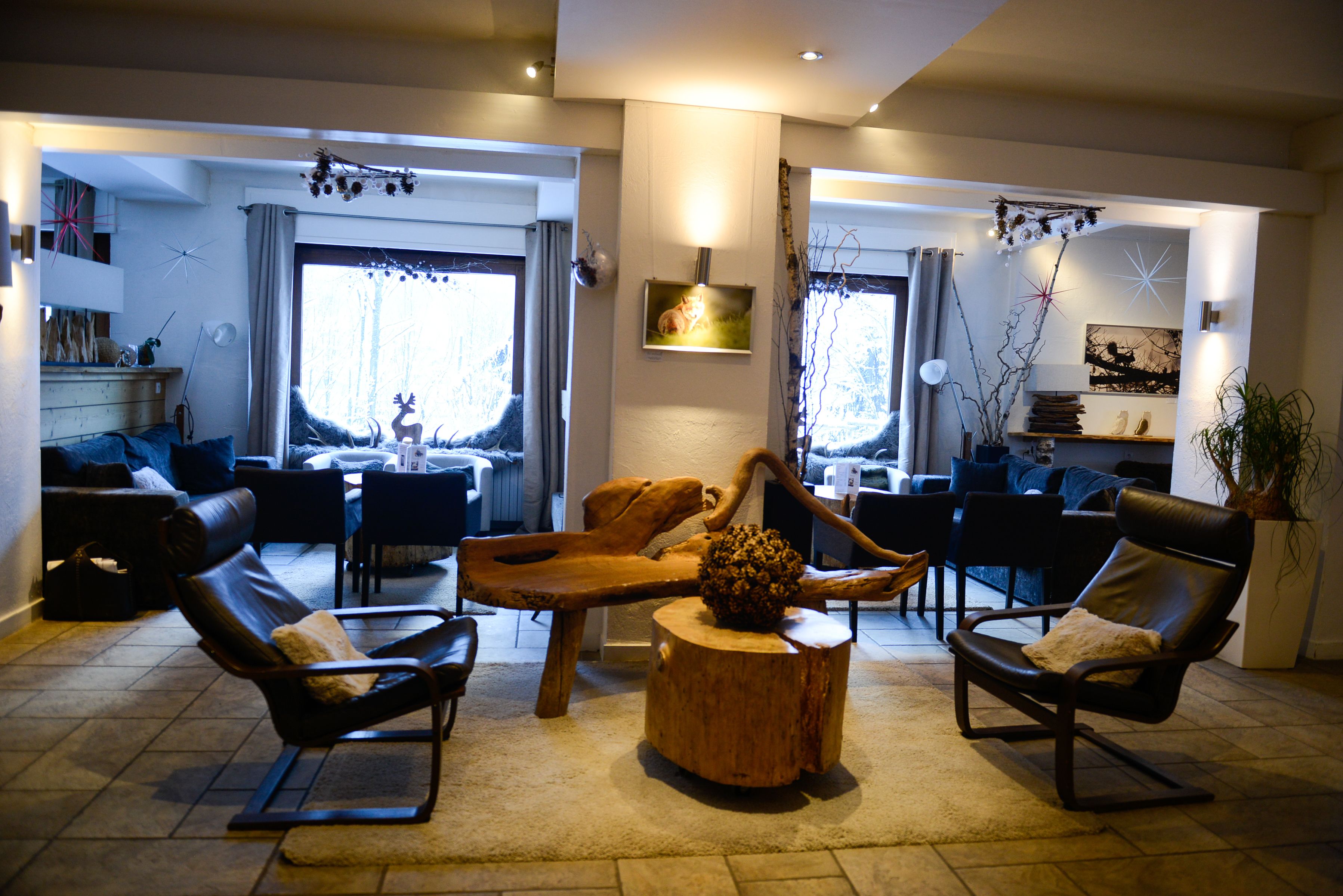A modern living room with a wooden coffee table, leather armchairs, and a dining area with a wooden table and chairs.